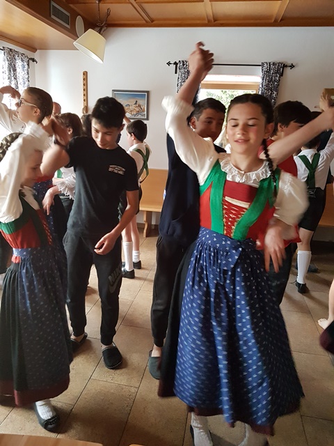 A group of boys and girls in traditional Austrian outfits dancing